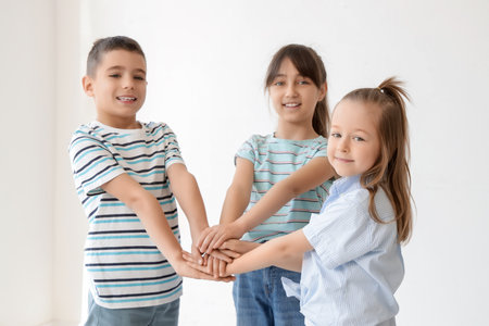 Cute little friends putting hands together in roomの写真素材