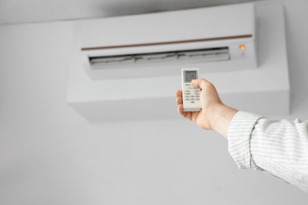 Male hand turning on air conditioner in room, closeupの写真素材