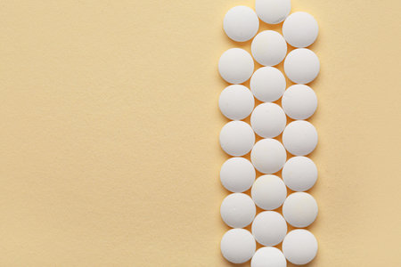 Many white pills on yellow background