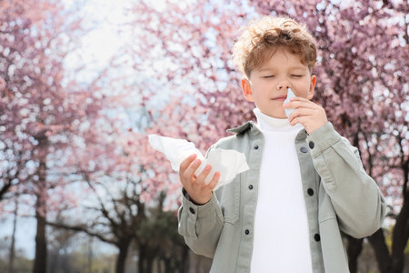 Sick little boy with nasal drops and tissue suffering from allergy outdoorsの写真素材