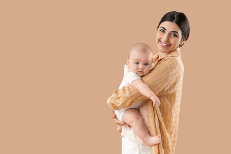 Young mother with her little baby on beige backgroundの写真素材