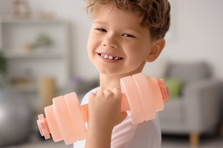 Sporty little boy exercising with dumbbell at home, closeupの写真素材