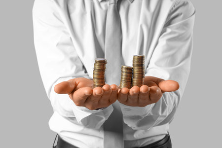 Businessman with coins on gray background, closeup