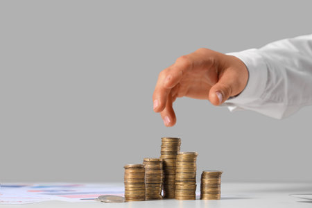 Person's hand counting coins on table against gray background