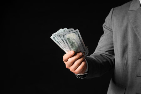 Businessman with money on black background, closeupの写真素材