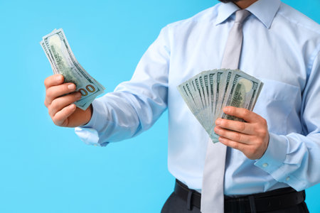 Businessman counting money on blue background, closeupの写真素材