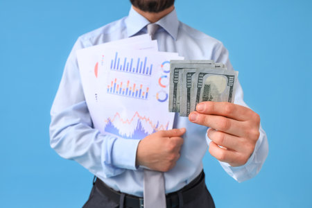 Businessman with money and graphs on blue background, closeupの写真素材