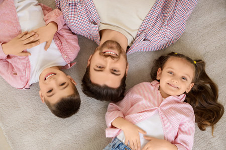 Happy father with his little children lying on carpet, top viewの写真素材