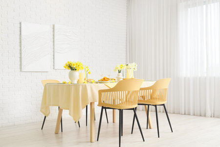 Elegant table setting with beautiful narcissus flowers in light dining room