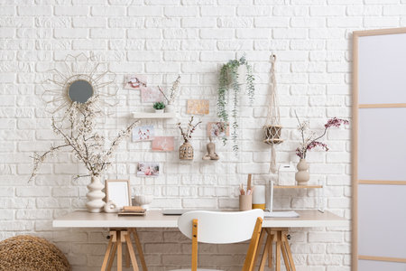 Interior of office with workplace, pin board and blossoming branches in vasesの写真素材