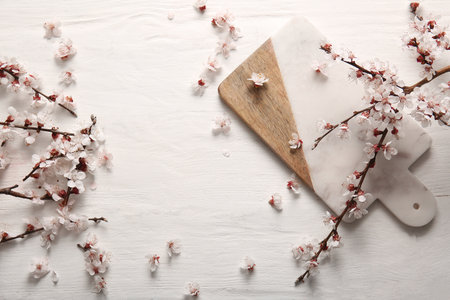 Cutting board with beautiful blooming branches and flowers on white wooden backgroundの写真素材