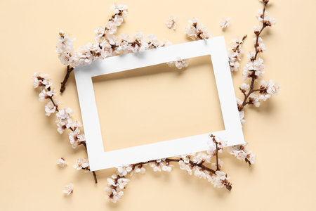 Paper frame with beautiful blooming tree branches on yellow background