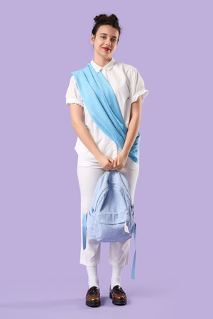 Female Indian student with backpack on lilac backgroundの写真素材