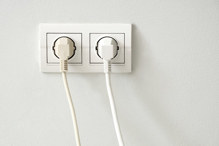 Socket with plugs on light wall, closeup