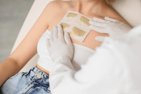 Female doctor applying mustard plaster on patient's chest in clinic, closeupの写真素材