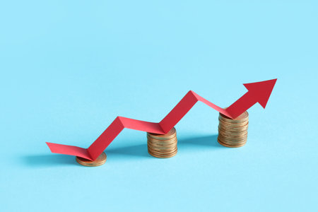 Arrow and coins on blue background. Concept of rising priceの写真素材