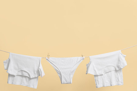Clean t-shirts and panties hanging on rope against color wallの写真素材