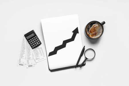 Notebook with arrow, calculator, bills and cup of coffee on light background. Concept of rising priceの写真素材