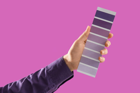 Female hand with violet paint palette swatches on color backgroundの写真素材