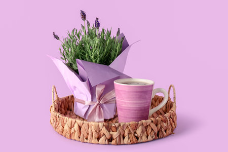 Pot with lavender, tray and cup of tea on lilac backgroundの写真素材