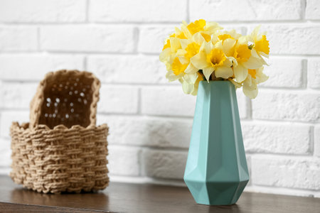 Vase with narcissus flowers and decor on dresser near white brick wall in living room, closeupの写真素材