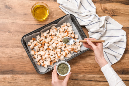 Young woman with seasonings preparing croutons on wooden backgroundの写真素材