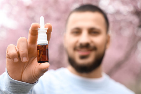Young man holding nasal drops outdoors, closeupの写真素材