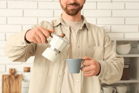 Young man with coffee maker and cup in kitchenの写真素材