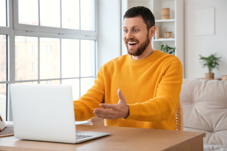 Surprised young man using laptop on table at homeの写真素材