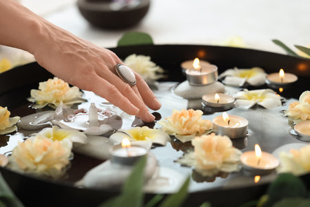 Woman with burning candles, flowers and stones in bowl of water, closeupの写真素材