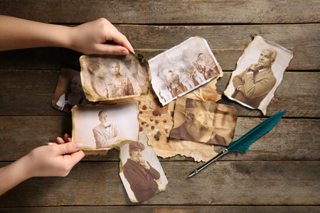 Female hands with old photos of relatives on wooden background. Concept of family tree
