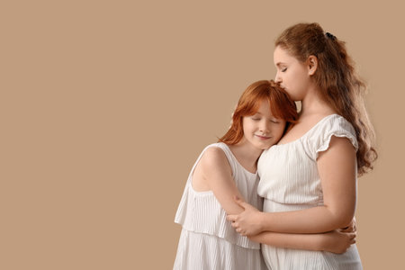 Beautiful young woman with her cute daughter hugging on brown background. Mother's Day celebrationの写真素材