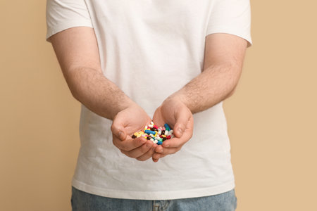 Young man with different pills on beige background, closeupの写真素材