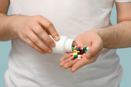 Young man with bottle of different pills on blue background, closeupの写真素材