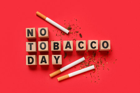 Text NO TOBACCO DAY made of wooden cubes and cigarettes on red backgroundの写真素材