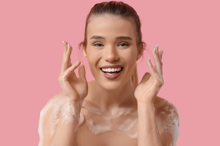 Happy young woman with foam on pink backgroundの写真素材