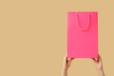 Female hands with pink shopping bag on brown backgroundの写真素材