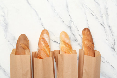 Paper bags with fresh baguettes on white backgroundの写真素材