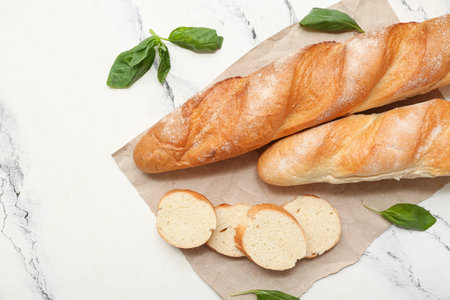 Paper with fresh baguettes and basil on white backgroundの写真素材