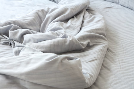 Cozy bed with crumpled gray blanket in bedroom, closeupの写真素材