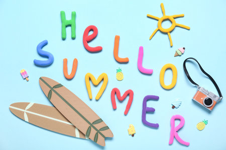 Composition with text HELLO SUMMER, mini surfboards and photo camera on color backgroundの写真素材