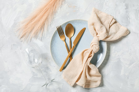 Beautiful table setting with golden cutlery and feathers on gray backgroundの写真素材
