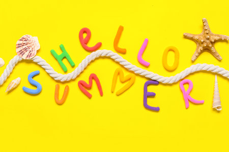 Composition with text HELLO SUMMER, rope and seashells on yellow backgroundの写真素材