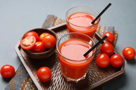 Glasses of fresh tomato juice and bowl with vegetables on dark background, closeupの写真素材