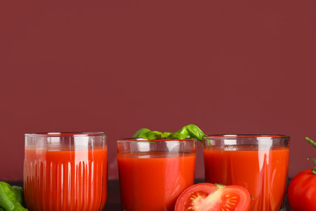 Glasses of fresh tomato juice with basil on color backgroundの写真素材