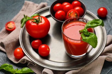 Glass of fresh tomato juice with basil and vegetables on dark background, closeupの写真素材
