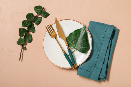 Beautiful table setting with golden cutlery and tree branch on beige backgroundの写真素材