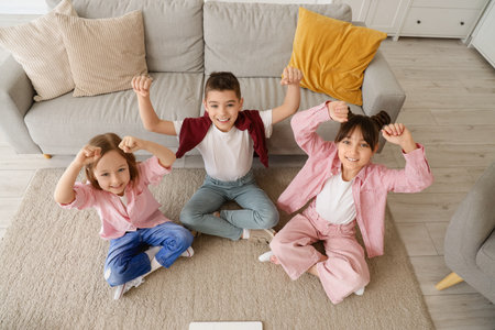 Happy little friends sitting on carpet at homeの写真素材
