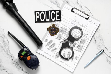 Handcuffs, fingerprints sheets, baton, walkie-talkie and police shield on light background