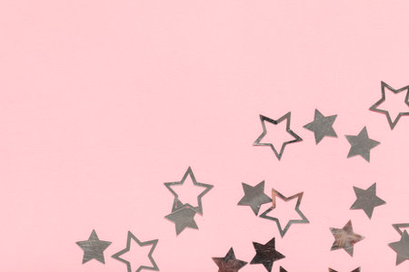 Beautiful silver confetti in the shape of star on pink backgroundの写真素材